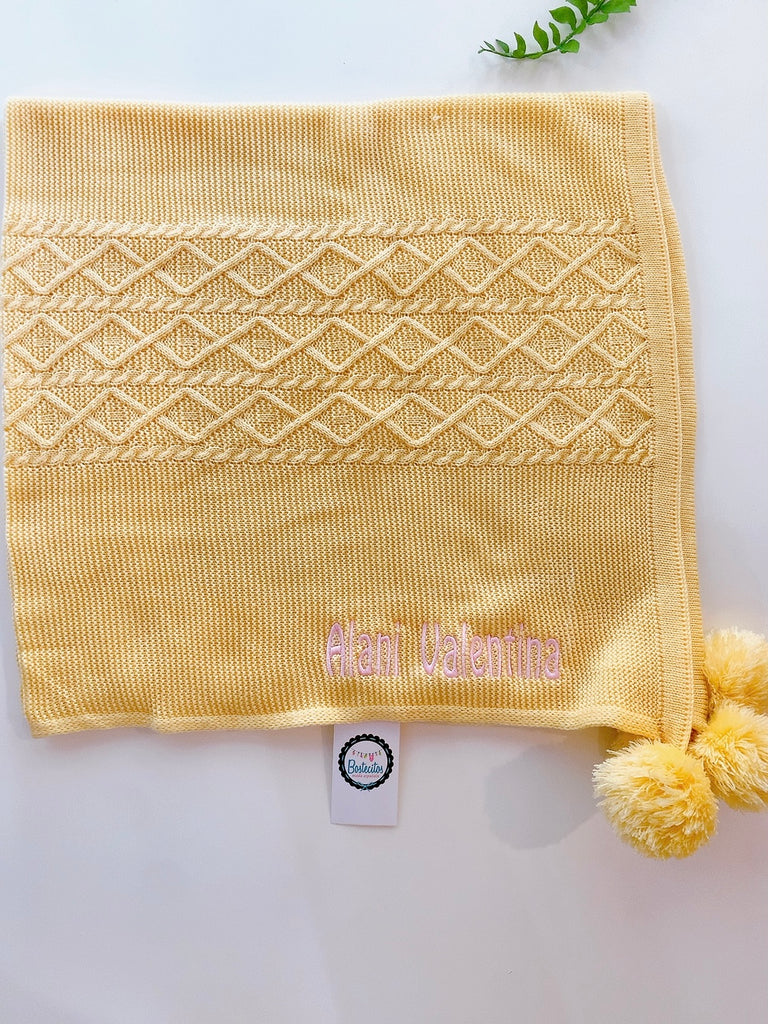 Cobija tejida amarilla con pompones